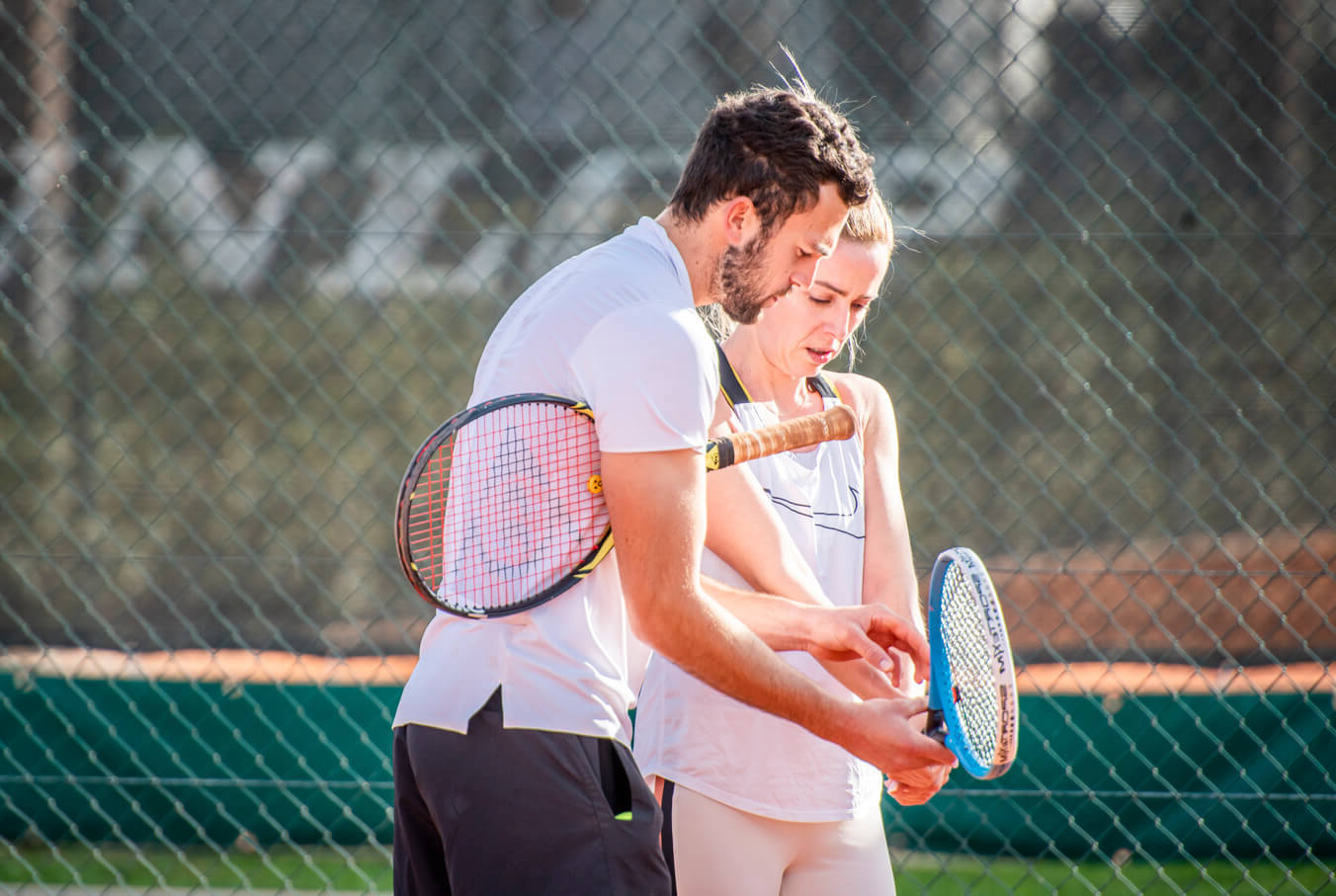 un homme qui apprend à une femme à faire du tennis